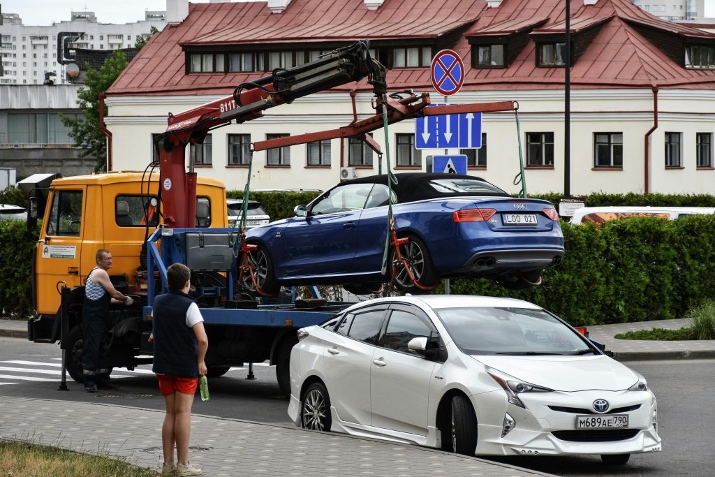 Towing a blue Audi convertible in a bustling city street.